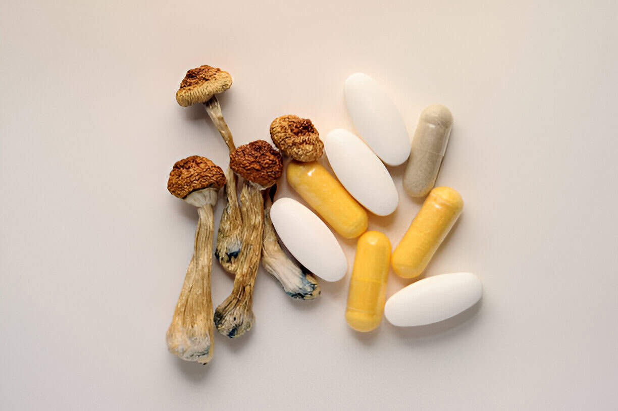 Mushrooms and various supplements including capsules and tablets on a neutral background, showcasing natural psychedelic products and health supplements.